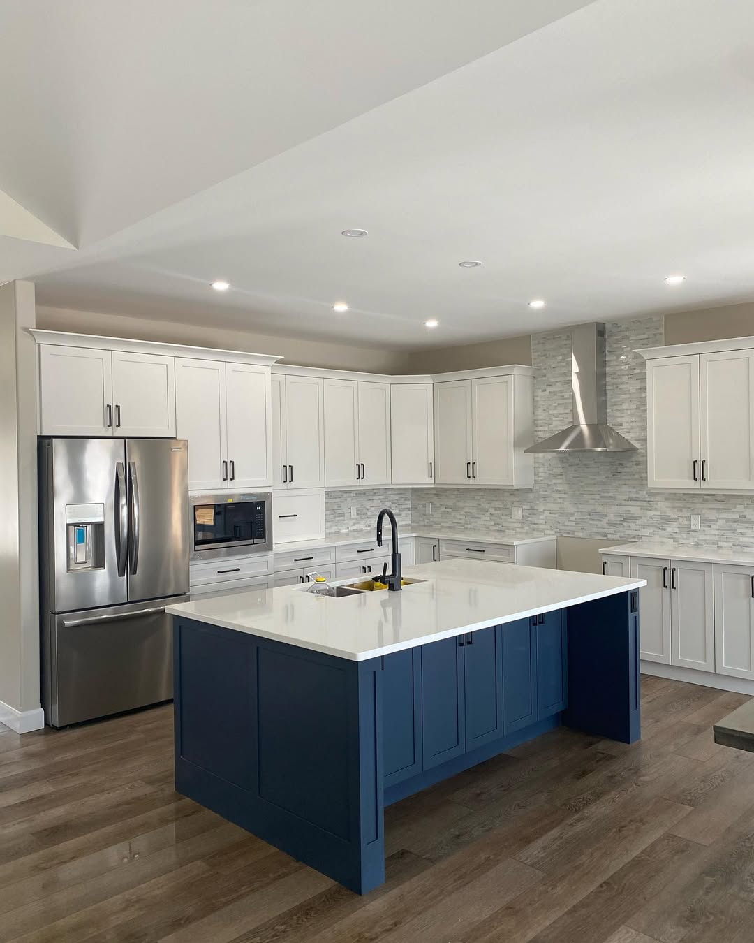 New kitchen with white cabinets and backsplash. Large blue kitchen island